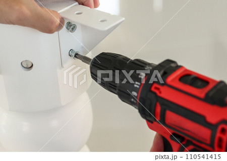 man assembling white table furniture at home using cordless screwdriver man assembling white table furniture at home using cordless screwdriver 110541415