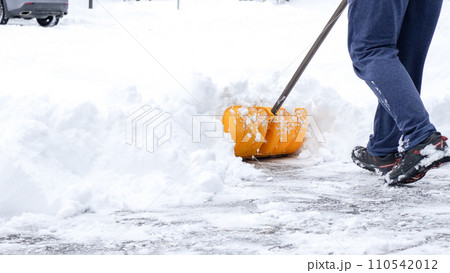 Man shoveling snow off of his driveway after a winter storm in Canada. Man with snow shovel cleans sidewalks in winter. Winter time. 110542012
