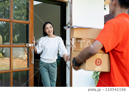 Young Asian cute girl receiving boxes from postman at the door. Delivery concept Young Asian cute girl receiving boxes from postman at the door. Delivery concept 110542198