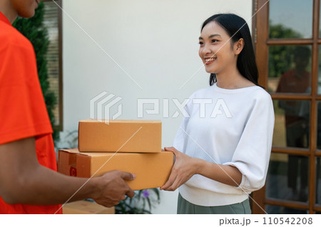 Young Asian cute girl receiving boxes from postman at the door. Delivery concept Young Asian cute girl receiving boxes from postman at the door. Delivery concept 110542208