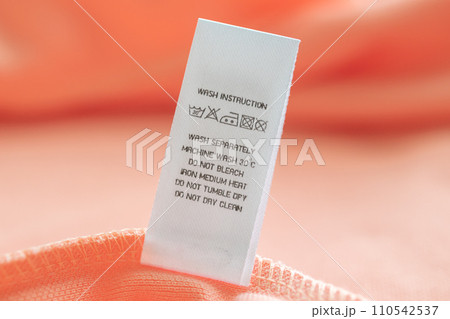 White laundry care washing instructions clothes label on pink cotton shirt White laundry care washing instructions clothes label on pink cotton shirt 110542537
