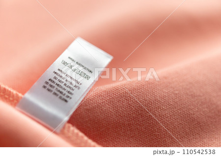 White laundry care washing instructions clothes label on pink cotton shirt White laundry care washing instructions clothes label on pink cotton shirt 110542538
