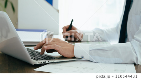 帳簿を確認する男性ビジネスマンの手元 110544431