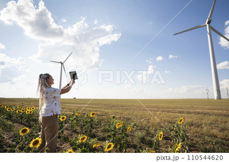 A blogger girl with bright braids shoots a story about green energy, about working with wind energy and wind turbines 110544620