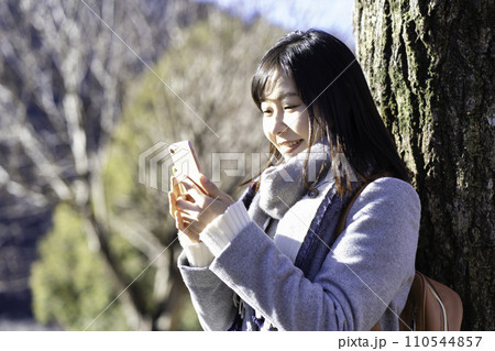 冬の公園でスマホを使う女性 110544857