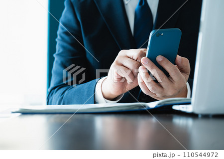 スマホでメールを送るビジネスマンの手元 110544972