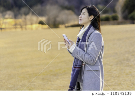 冬の公園でスマホを使う女性 110545139