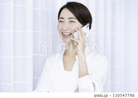 リビングでスマホ通話するミドルの女性 110547798
