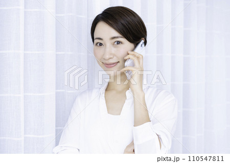 リビングでスマホ通話するミドルの女性 110547811