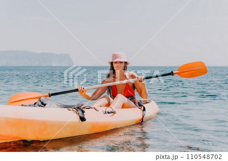 Woman sea kayak. Happy smiling woman paddling in kayak on ocean. Calm sea water and horizon in background. Active lifestyle at sea. Summer vacation. Woman sea kayak. Happy smiling woman paddling in kayak on ocean. Calm sea water and horizon in background. Active lifestyle at sea. Summer vacation. 110548702