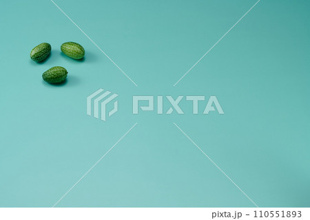 マイクロきゅうりを数粒左上に配置した緑色系背景あり俯瞰撮影 110551893