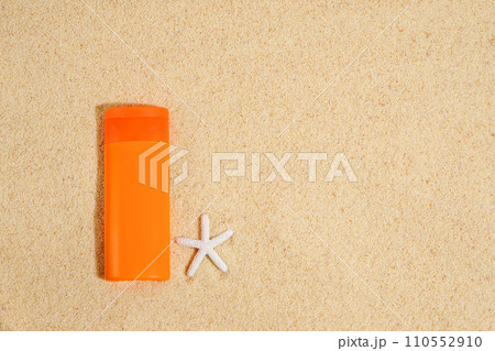Sunscreen in orange plastic tube with white starfish on sand background . Sunscreen with UVA and UVB protection. Summer, sea 110552910