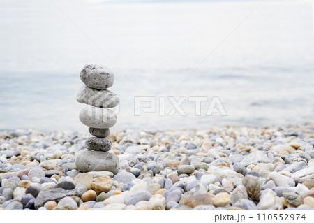 Pyramid of pebbles on the sea beach.Waves in background Pyramid of pebbles on the sea beach.Waves in background 110552974
