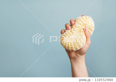 Natural washcloth in the female hand on blue background with copy space Natural washcloth in the female hand on blue background with copy space 110552980