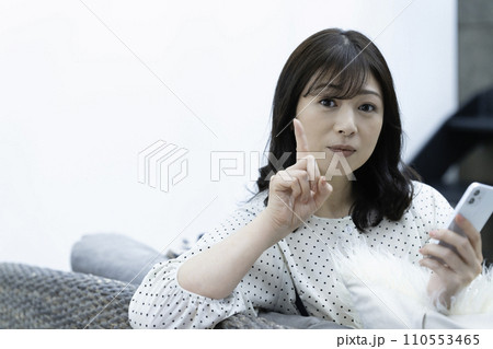 リビングのソファーでスマホを使うミドル女性 リビングのソファーでスマホを使うミドル女性 110553465