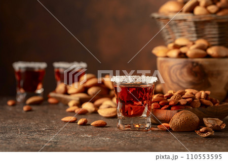 Italian liqueur Amaretto with almonds nuts on a brown background. Italian liqueur Amaretto with almonds nuts on a brown background. 110553595