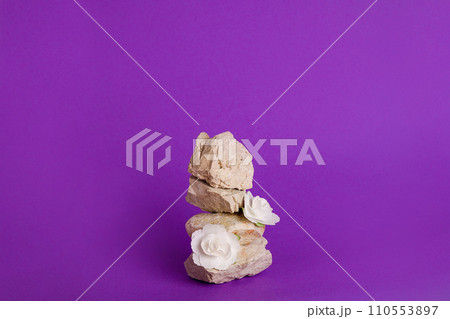 Empty stack of stones podium with paper flowers on violet background. Minimal empty display product presentation scene Empty stack of stones podium with paper flowers on violet background. Minimal empty display product presentation scene 110553897