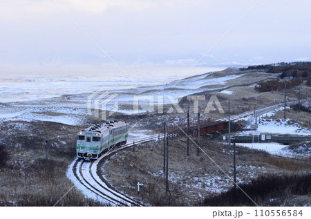 寒風吹き荒ぶオホーツク海沿いを行く釧網本線の普通列車 110556584