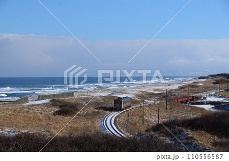 冬の陽射しを浴びてオホーツク海沿いを往く釧網本線の普通列車（後追い） 110556587