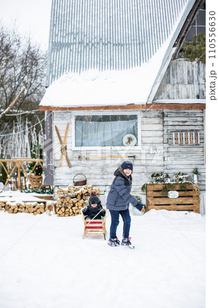 Boy pulling his friend on a sledge 110556630