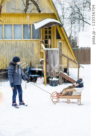 Boy pulling his friend on a sledge 110556704
