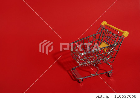 Shopping trolley on red background with copy space 110557009