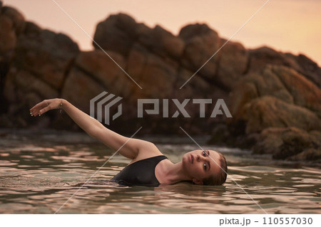 Woman relaxes in sea at sunset, serene natural swim, embodies wellness, eco therapy. Fitness, solitude with aquatic beauty celebrate health, mindfulness in nature. Vacation, leisure coastal experience Woman relaxes in sea at sunset, serene natural swim, embodies wellness, eco therapy. Fitness, solitude with aquatic beauty celebrate health, mindfulness in nature. Vacation, leisure coastal experience 110557030