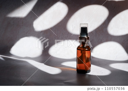Cosmetic oil in glass bottle bottle on concrete background with reflections and contrasting shadows 110557036