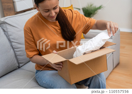 With excitement, a shopaholic woman inspects her parcel, validating contentment through e-commerce and express online shopping With excitement, a shopaholic woman inspects her parcel, validating contentment through e-commerce and express online shopping 110557556