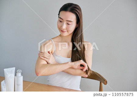 二の腕にクリームを塗ってボディケアする30代女性 110557875