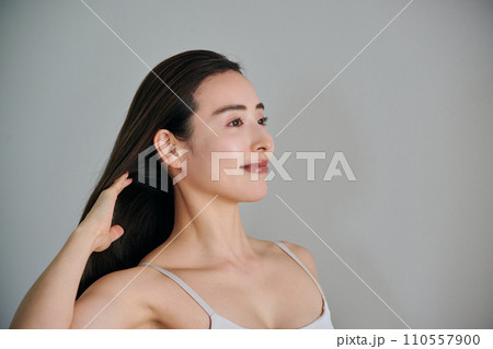 髪をかきあげるロングヘアの30代女性 110557900