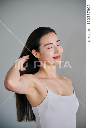 髪をかきあげるロングヘアの30代女性 110557903