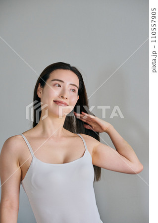 髪をかきあげるロングヘアの30代女性 110557905
