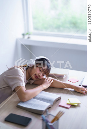 Young asian student in casual clothes wear headphones to listening music and sleep to resting on desk after reading a book and studying education knowledge to doing homework assignments in university Young asian student in casual clothes wear headphones to listening music and sleep to resting on desk after reading a book and studying education knowledge to doing homework assignments in university 110559770