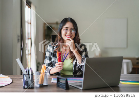 Female artist designer holding color pencils and working to designing graphic design of logo brand 110559818