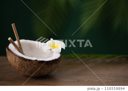 Half of coconut with coconut water on wooden table. Tropical summer healthy coconut cocktail. Half of coconut with coconut water on wooden table. Tropical summer healthy coconut cocktail. 110559894