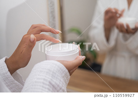 Radiant skin: A woman's hands, in close-up, hold a jar of rejuvenating cream in her bathroom, enhancing her skincare. Radiant skin: A woman's hands, in close-up, hold a jar of rejuvenating cream in her bathroom, enhancing her skincare. 110559927