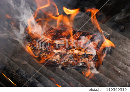 Searing and smoking ribeye steaks on grill 110560559