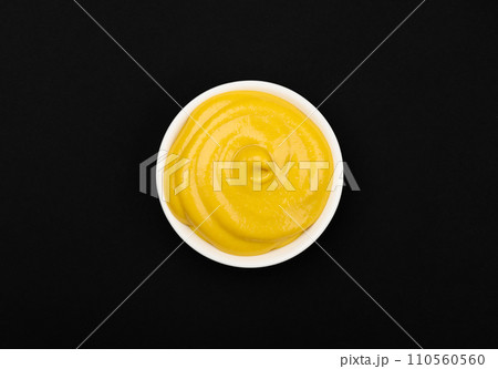 White bowl of yellow American mustard on table 110560560