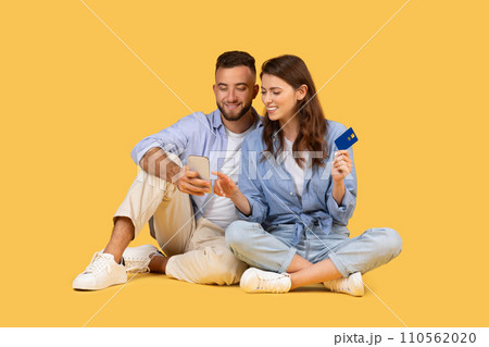 Couple with phone and credit card, engaged in online shopping 110562020