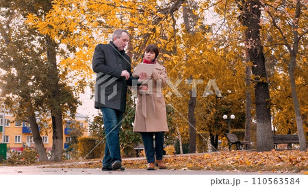 Man and woman discuss company work at business meeting in city park in autumn Man and woman discuss company work at business meeting in city park in autumn 110563584