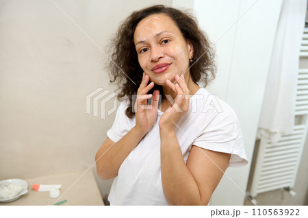 Young woman touching face, taking care of her flawless skin, applying cleansing foam, smiling cutely looking at camera Young woman touching face, taking care of her flawless skin, applying cleansing foam, smiling cutely looking at camera 110563922