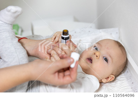 Mom giving vitamin D3 to newborn baby for care of the proper functioning of muscles and bone formation, healthcare concept 110564096