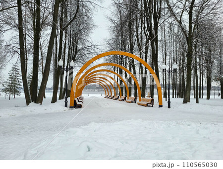 Semicircular wooden arcade with lamps in the park in winter 110565030