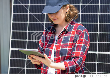 Woman with digital tablet next to solar power station 110565266
