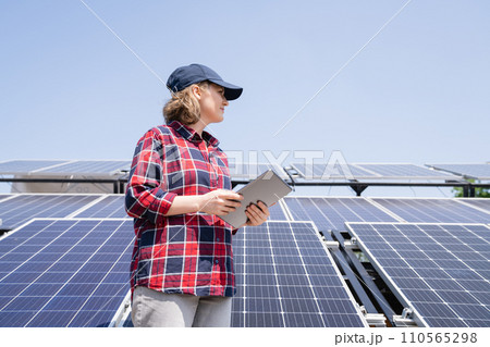 Woman with digital tablet next to solar power station 110565298
