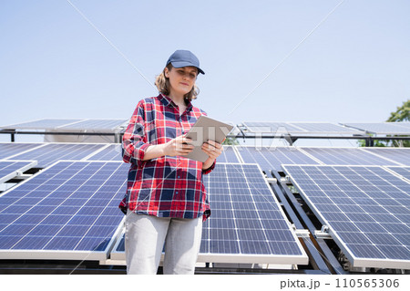 Woman with digital tablet next to solar power station 110565306