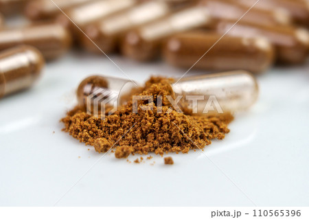 Nutrient supplement powder and broken brown herbal medicine capsule. Alternative medicine drug 110565396