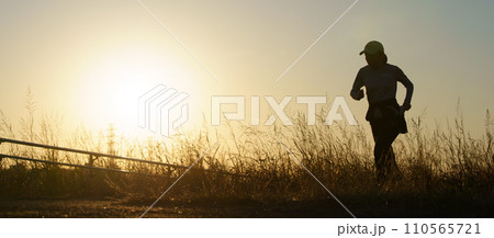 夕日とジョギングする人のシルエット 110565721