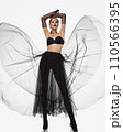 Beautiful woman in a transparent black skirt, bodice and neck decoration posing on a white background 110566395